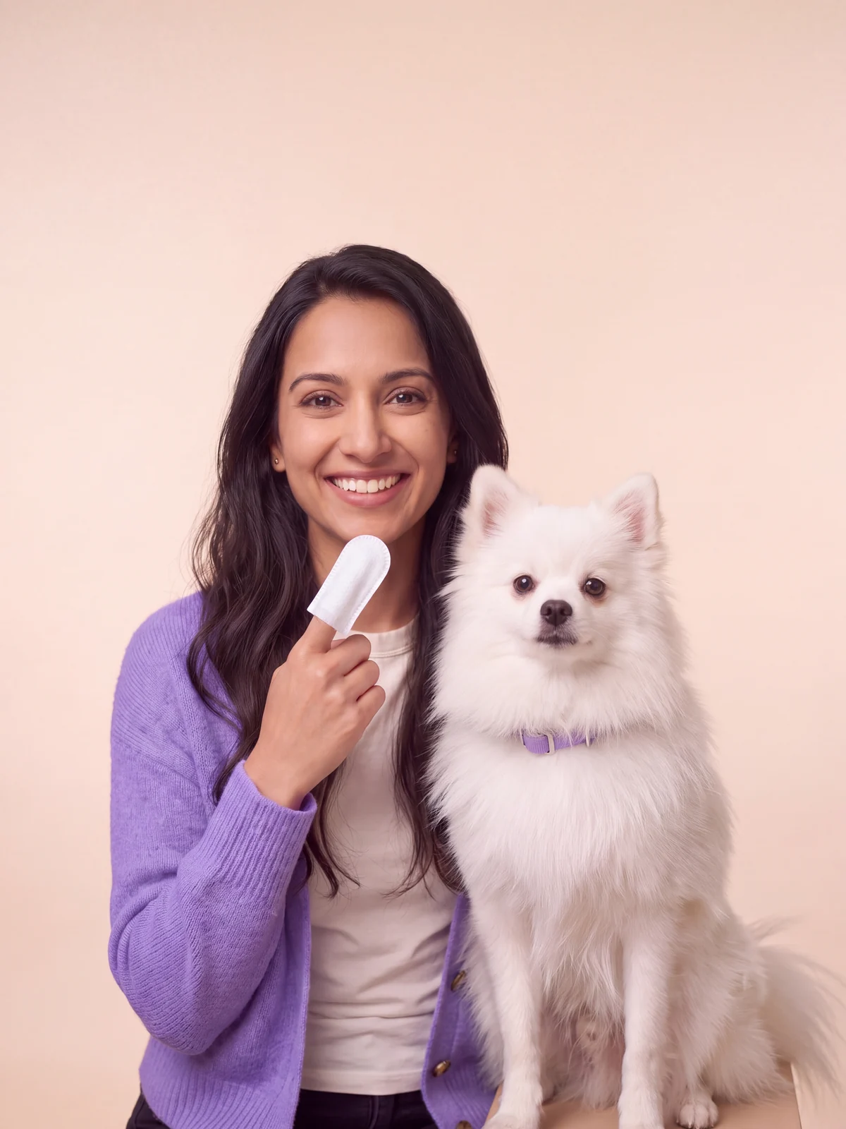 Maya holding up an ear finger wipe next to Mochi, her Pomeranian