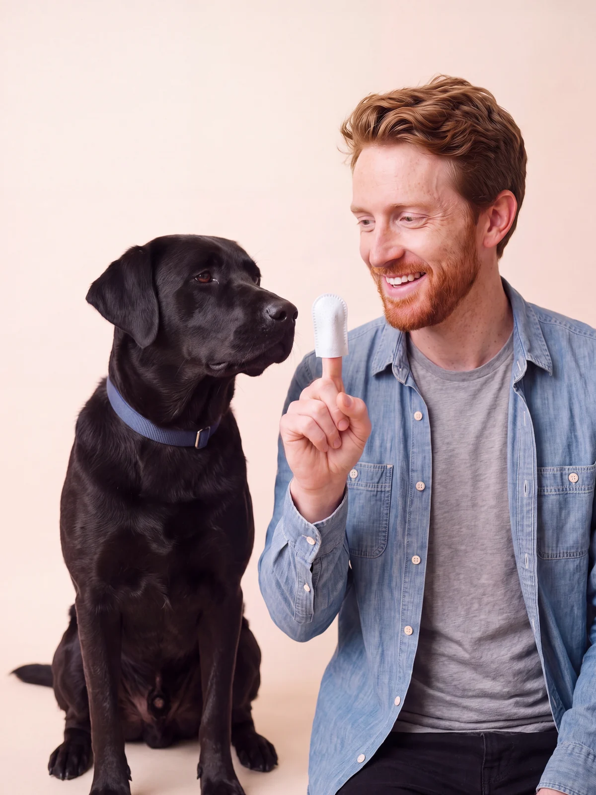 Ryan holding up a finger wipe next to Bear, his black Labrador